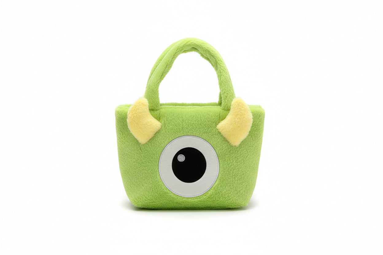 Green plush bag with a single eye and yellow ears on a white background